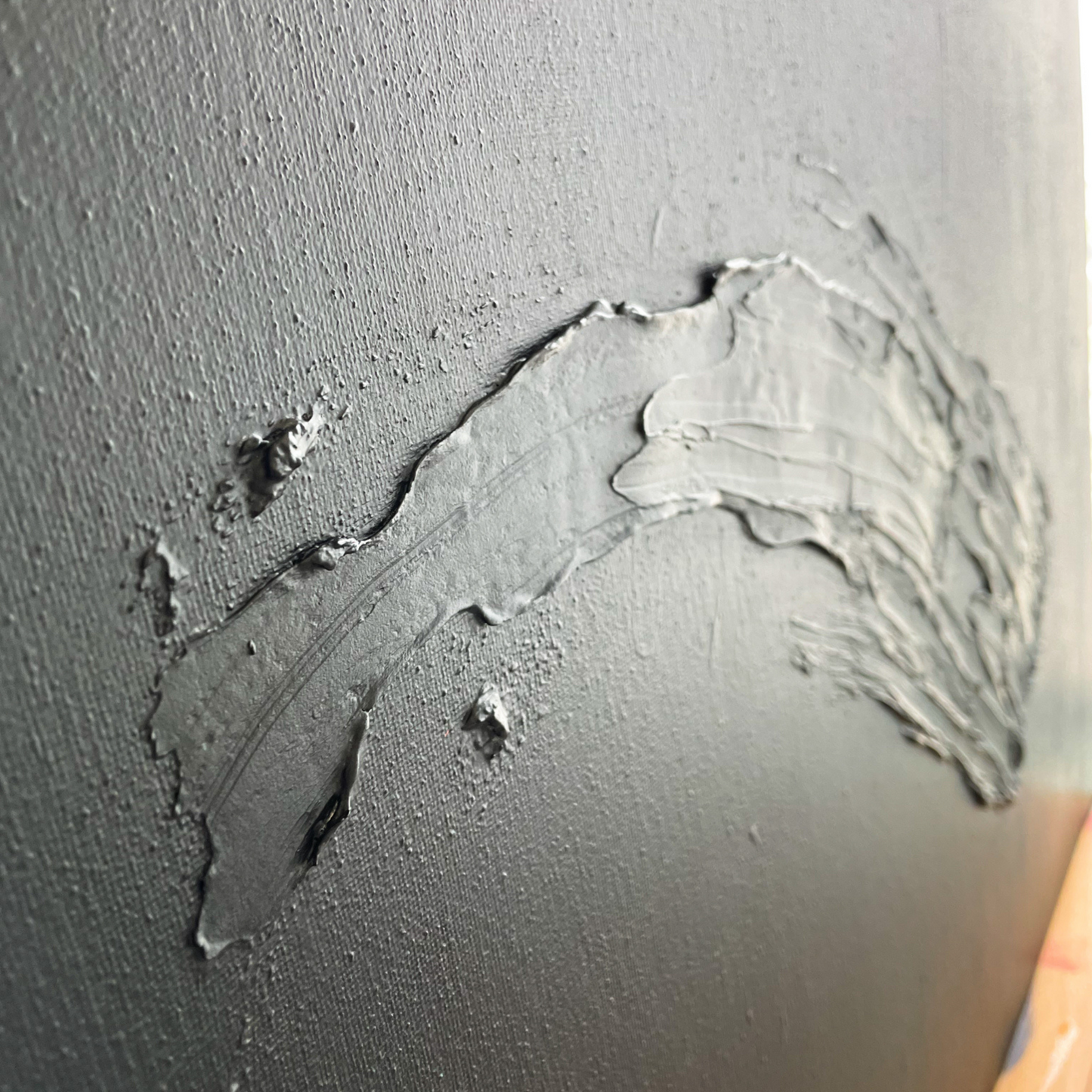 The side view of a black painting with a large textured downward swoosh.
