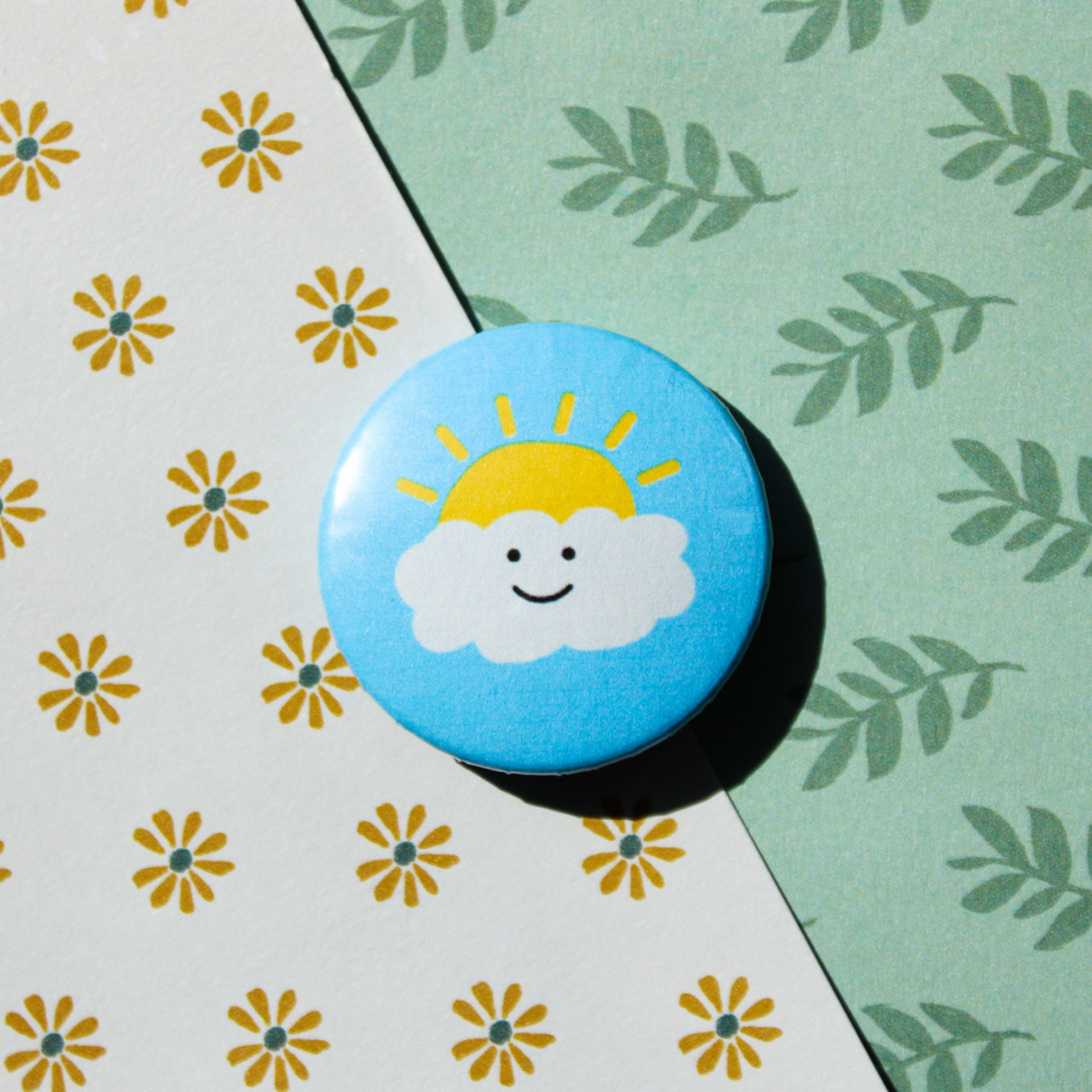 A leaf and floral pattern background. On top is a blue circle button a white smiling cloud and a yellow sun peeping out behind it.
