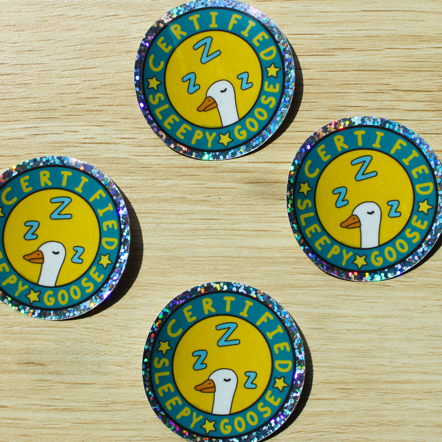 Four certified sleepy goose holographic circle stickers placed on a wooden background