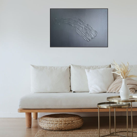 A cream couch on a wooden floor with a white wall in the background. Hanging on the white wall is a black painting with a large textured downward swoosh.