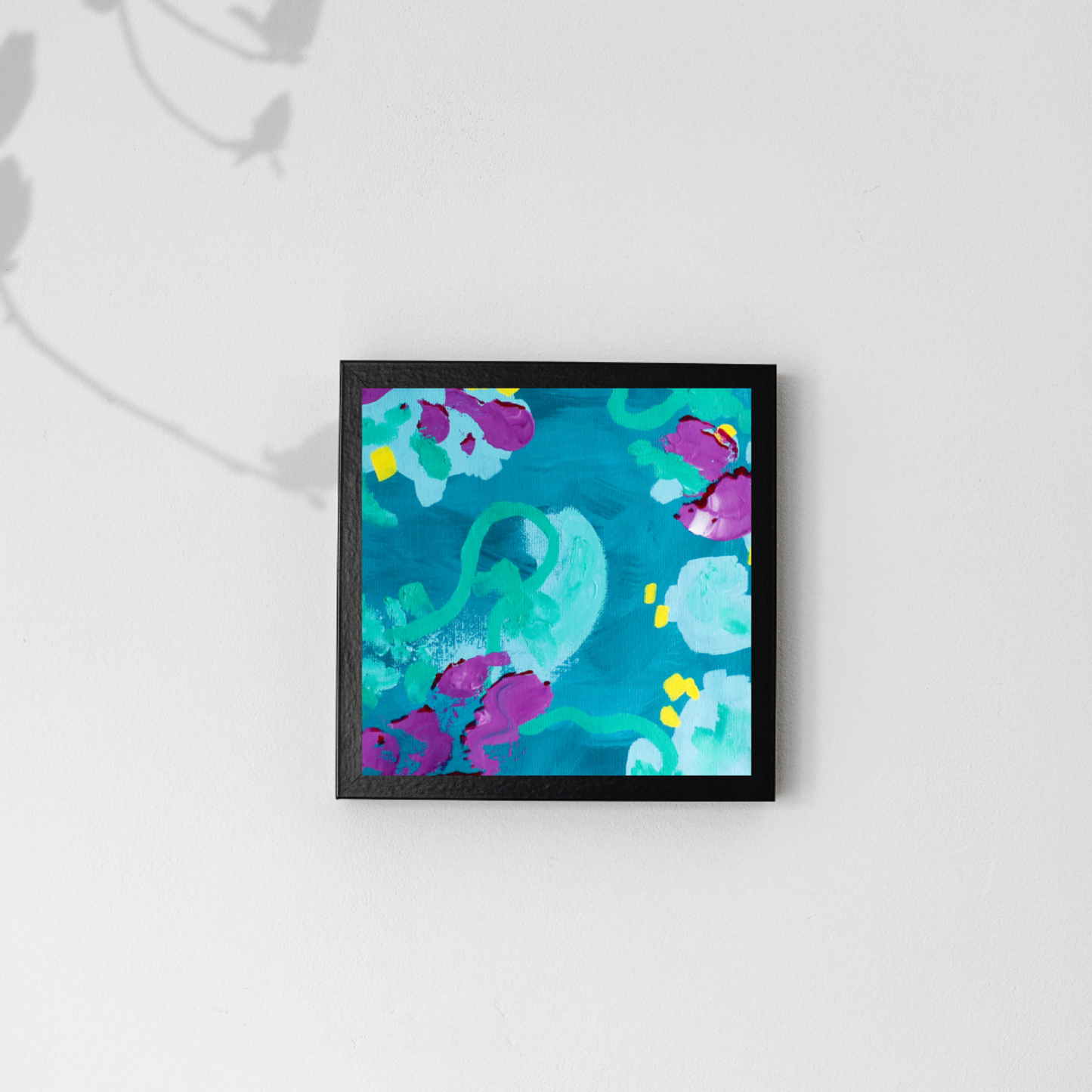 A grey wall with a shadow in the top left corner. In the middle is a black frame with an abstract blue, turquoise, and purple painting.